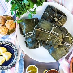 some food is wrapped in paper on a plate with dipping sauces next to it