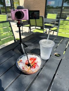 a camera is set up to take pictures of food on a picnic table in front of a building