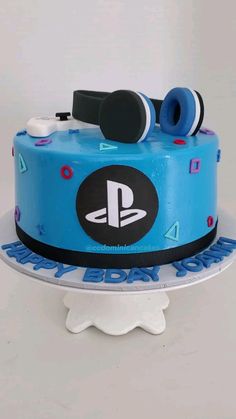 a blue playstation cake with headphones on top