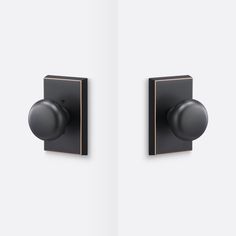 two black knobs on the side of a white wall and one has an open door