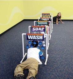 a child laying on the floor in front of a row of chairs with signs attached to them