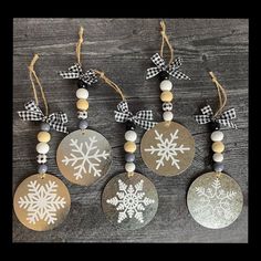 four snowflake ornaments hanging from string on wooden table with black and white checkered ribbon