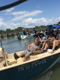 a group of people sitting in a boat on the water with camera equipment around them