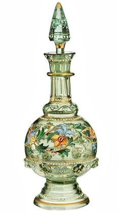 a green vase with flowers painted on it's sides and an ornate design around the top