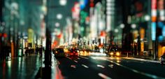 a city street filled with lots of traffic next to tall buildings and lights at night