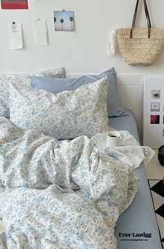 an unmade bed with blue and white sheets, pillows and pictures on the wall