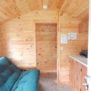 the interior of a tiny cabin with wood walls and flooring, including a blue couch