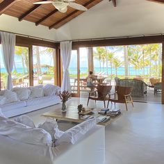 a living room filled with white furniture and lots of windows overlooking the ocean on a sunny day