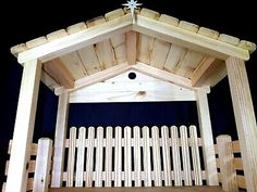 a nativity scene made out of wood with a star on the roof and fence