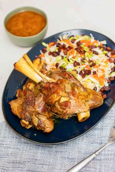 a blue plate topped with meat and rice next to a bowl of chili sauce on a table