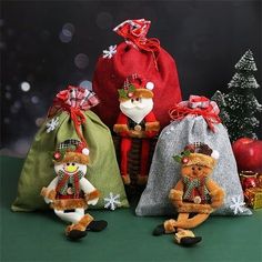 three stuffed animals are sitting in front of some christmas trees and bags with santa claus on them