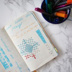 an open notebook sitting on top of a table next to markers and pencils,