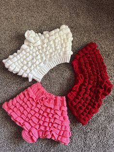 three pieces of crocheted clothing laying on the floor next to eachother