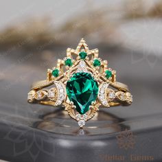 an emerald and diamond ring on top of a phone