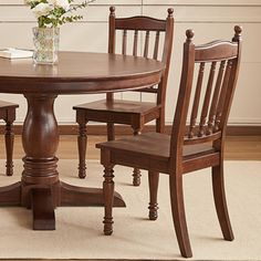 a dining room table with chairs and a vase filled with flowers on top of it