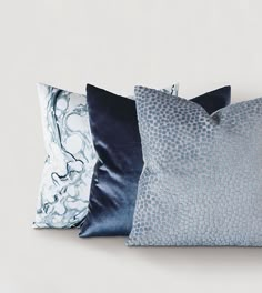 three blue and white pillows sitting next to each other