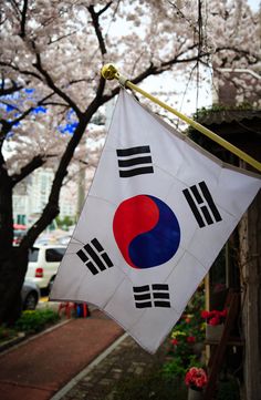 a flag hanging from the side of a building with cherry blossom trees in the background