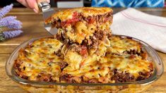 a person is cutting into some lasagna casserole on a wooden table