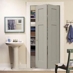 an open door in a bathroom next to a sink and chair with towels hanging on the wall