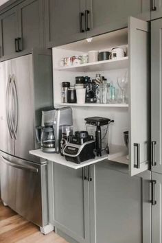 a kitchen with gray cabinets and stainless steel appliances on the counter top, along with an open refrigerator