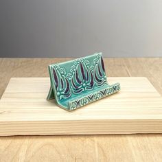 a small blue and green ceramic object sitting on top of a wooden board