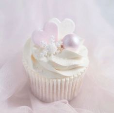 a cupcake with white frosting and pink decorations