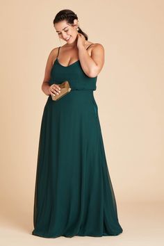 a woman in a dark green dress is smiling and holding her hand to her ear