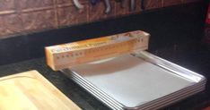 a stack of silver plates sitting on top of a counter next to a box of paper