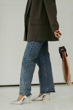 a woman in high heels is holding an umbrella and a small dog leashed to her side