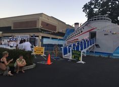 two people sitting on the ground in front of a cruise ship