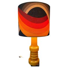 a lamp that is sitting on top of a wooden stand with a fabric shade over it