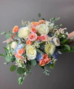 a bridal bouquet with peach, white and blue flowers on grey background in close up