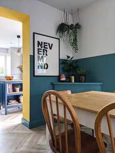 a dining room table with two chairs next to a blue cabinet and potted plant