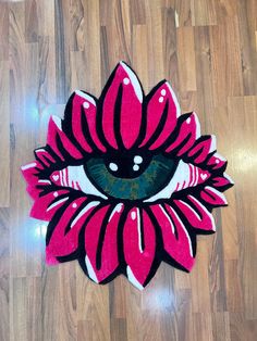 a pink and black flower with an eye on it's center is sitting on the floor