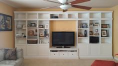 a living room filled with furniture and a flat screen tv mounted on a white wall