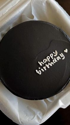 a black birthday cake in a white box with writing on the top and happy birthday written on it