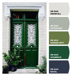 a green door with white trim on it and some potted plants next to it