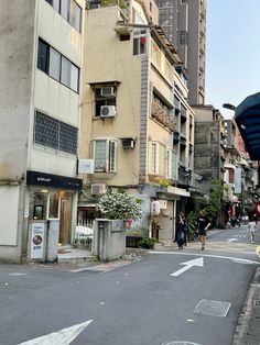 people are walking down the street in front of some tall buildings with balconies