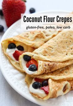 three crepes on a white plate with berries and blueberries in the background