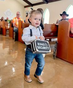 a little boy in suspenders holding a sign that says ring and security