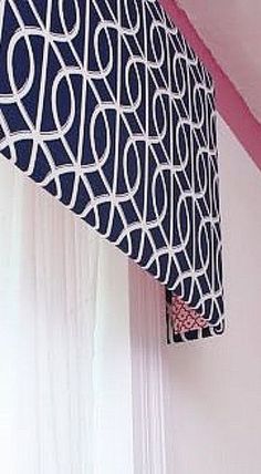 a close up of a bed in a room with pink walls and curtains on the window sill