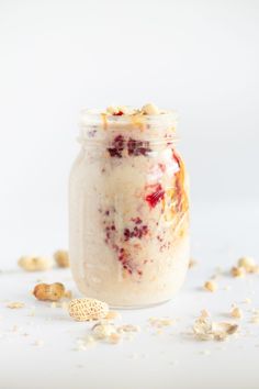 a jar filled with oatmeal sitting on top of a white table next to nuts