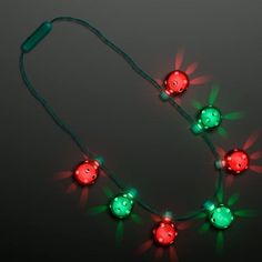 a string of christmas lights with green and red balls on them, all lit up