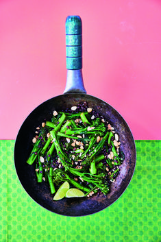 a frying pan filled with asparagus and nuts on top of a table