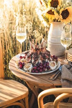 a plate with food on it sitting next to some wine glasses and sunflowers