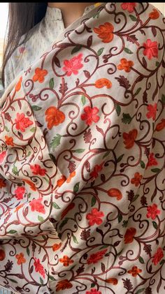 a woman wearing a white shirt with red and orange flowers on it