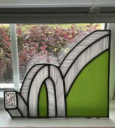 a green and white sculpture sitting on top of a window sill