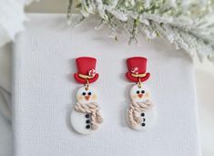 the snowman earrings are decorated with red hats