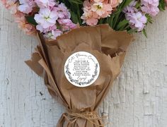 a bouquet of pink and white flowers wrapped in brown paper with a label on it