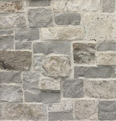 a stone wall that has been made out of different types of stones and is grey